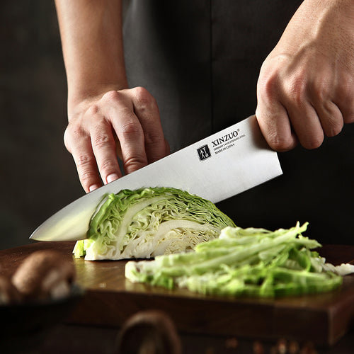Chef usando cuchillo profesional Xinzuo de acero alemán de 8 pulgadas para picar col en tabla de madera.