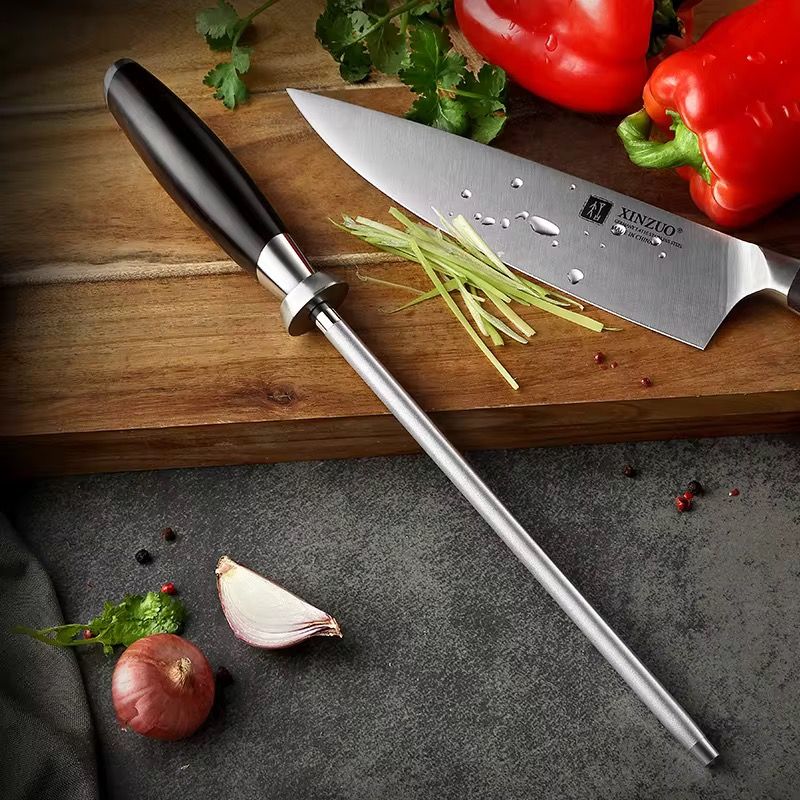 Chaira de diamante profesional Xinzuo B21-E con mango de ébano junto a cuchillo de chef y vegetales frescos.