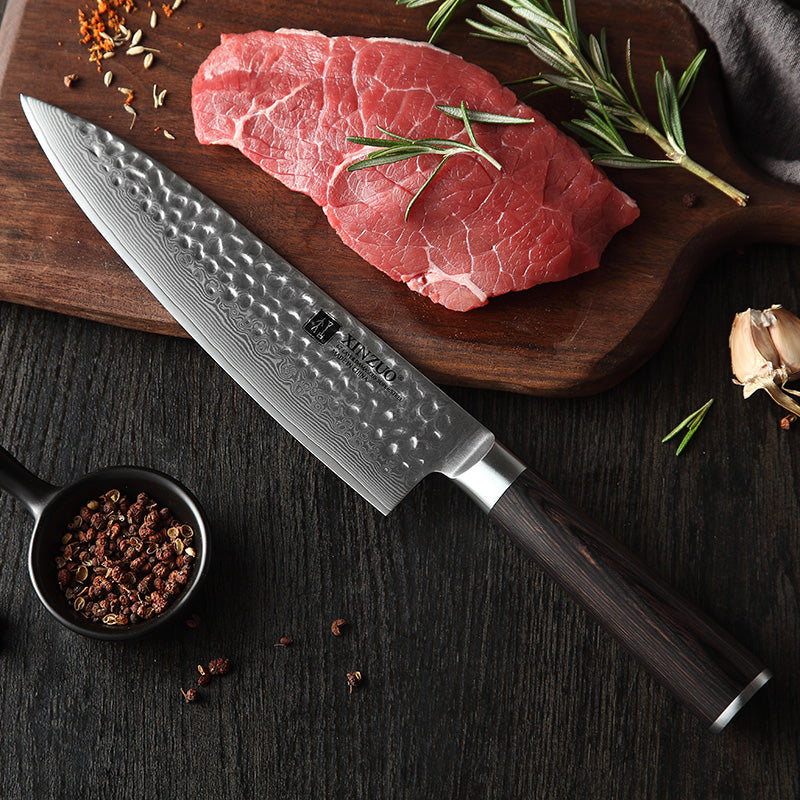 Cuchillo Xinzuo Chef de 8 pulgadas en acero Damasco con mango de madera junto a corte de carne en tabla.