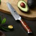 Cuchillo Chef Xinzuo de acero Damasco de 67 capas con mango de madera Rosewood, junto a un aguacate en tabla de madera.