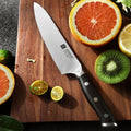 Cuchillo utilitario Xinzuo de 5 pulgadas en acero alemán y mango de ébano sobre tabla de madera con cítricos.