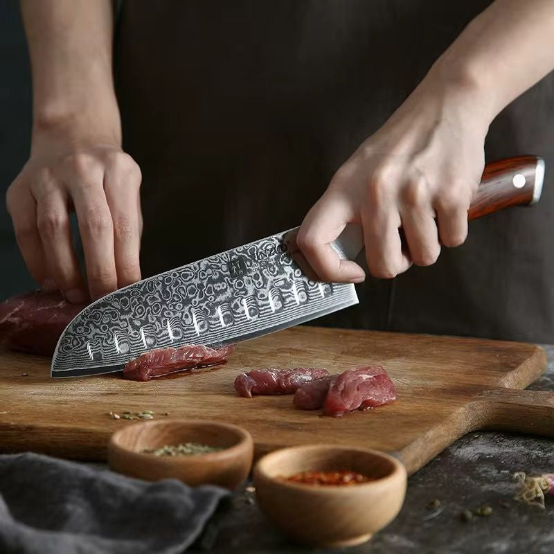 Cuchillo Santoku Xinzuo de acero de Damasco cortando carne sobre tabla de madera, uso profesional de cocina.
