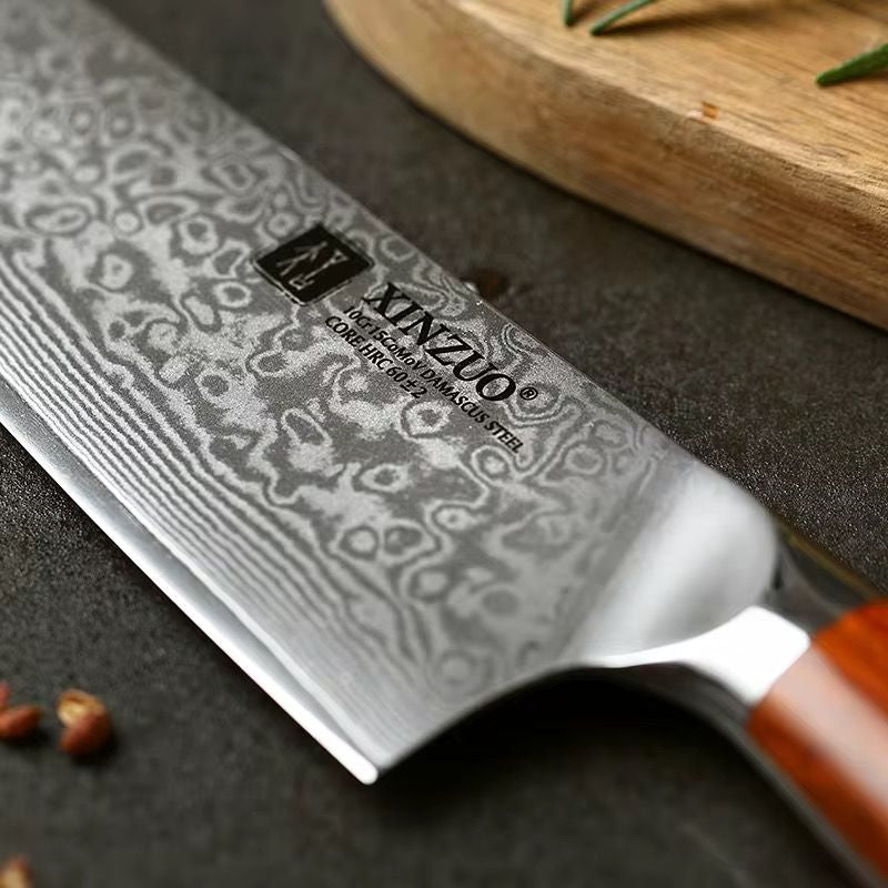 Primer plano de cuchillo profesional Xinzuo de acero de Damasco con 67 capas y mango de madera sobre tabla.
