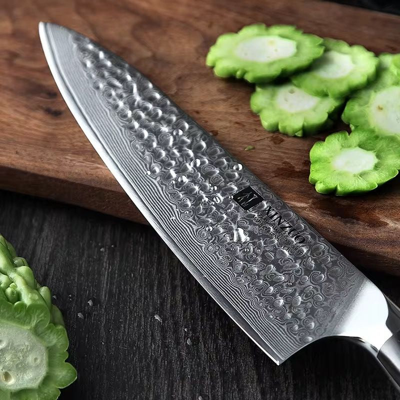 Cuchillo de chef XINZUO de acero de Damasco con hoja de 67 capas sobre tabla de madera con vegetales.